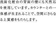 天然石洗面立上り　洗面化粧台の背面の壁にも天然石を使用しています。カウンターとの一体感が生まれることで、空間にさらなる上質感をもたらします。