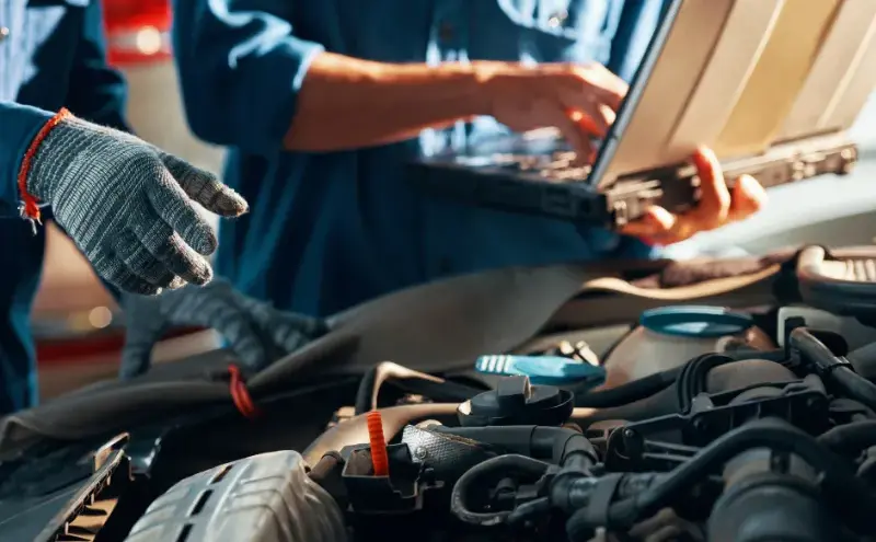 整備士が車のエンジンを診断テスターで点検する様子